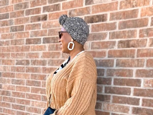 woman smiling and looking into the distance. wearing a cute black and white pre-tied headwrap