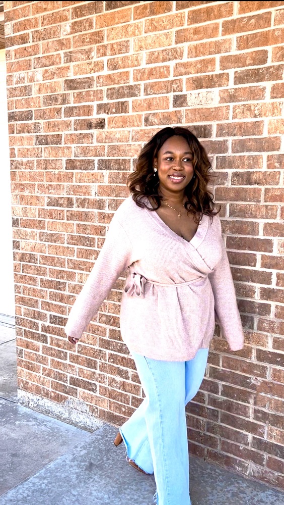 plus size woman wearing light pink v-neck sweater, light wide leg jeans and suede knee high boots