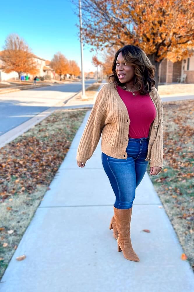woman looking into the distance wearing a cute jeans outfit with cardigan, and brown suede boots