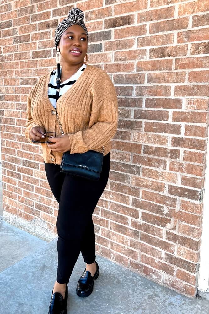 black woman wearing a brown cardigan, striped t-shirt, black pants, and black and white headwrap