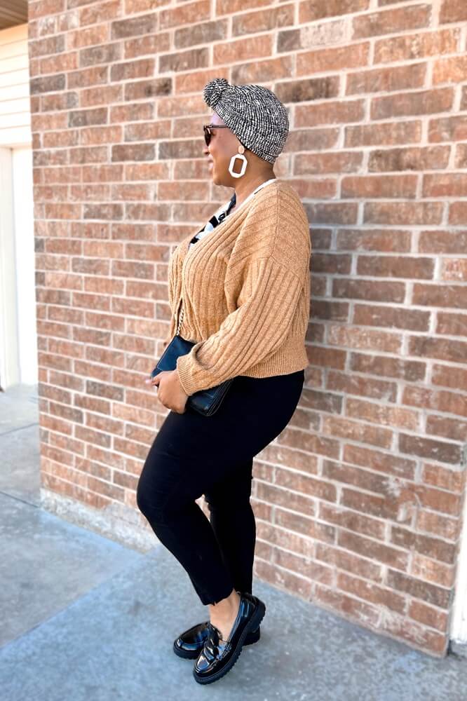 this woman is giving a masterclass in how to look put together as a stay at home mom. she's wearing a cute cropped sweater, black slim trousers, black lug sole loafers, and a stylish neutral pattern headwrap 