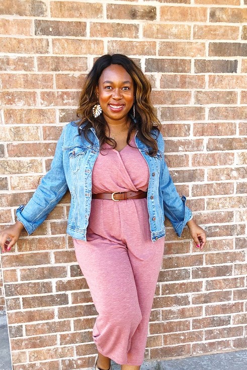 black woman wearing a soft pink jumpsuit and denim ajcket 